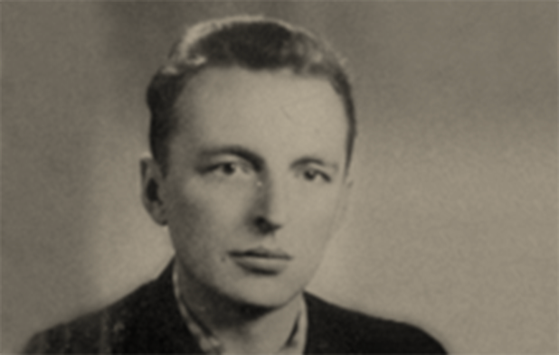 Czarno-białe zdjęcie portretowe dwudziestopięcioletniego Stanisława. Zdjęcie przedstawia jego popiersie. Mężczyzna ma krótkie, zaczesane do tyłu włosy oraz pełne usta. Ubrany jest w kraciastą koszulę i ciemną marynarkę.